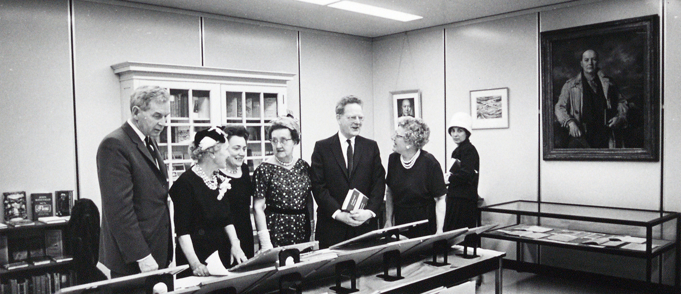 Northrop Frye at the the dedication of the E.J. Pratt Room of Contemporary Poetry on 15 October, 1964 in Victoria University Library. Looking at the exhibit are President A.B.B. Moore, Viola Whitney Pratt, Claire Pratt, Florence Pratt, Principal Frye with the Librarian Margaret Ray