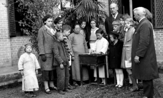 Child reading, while Pastor Wang Lieh-guang and missionaries look on, [ca 1920s]. Credit: Walmsley Family.